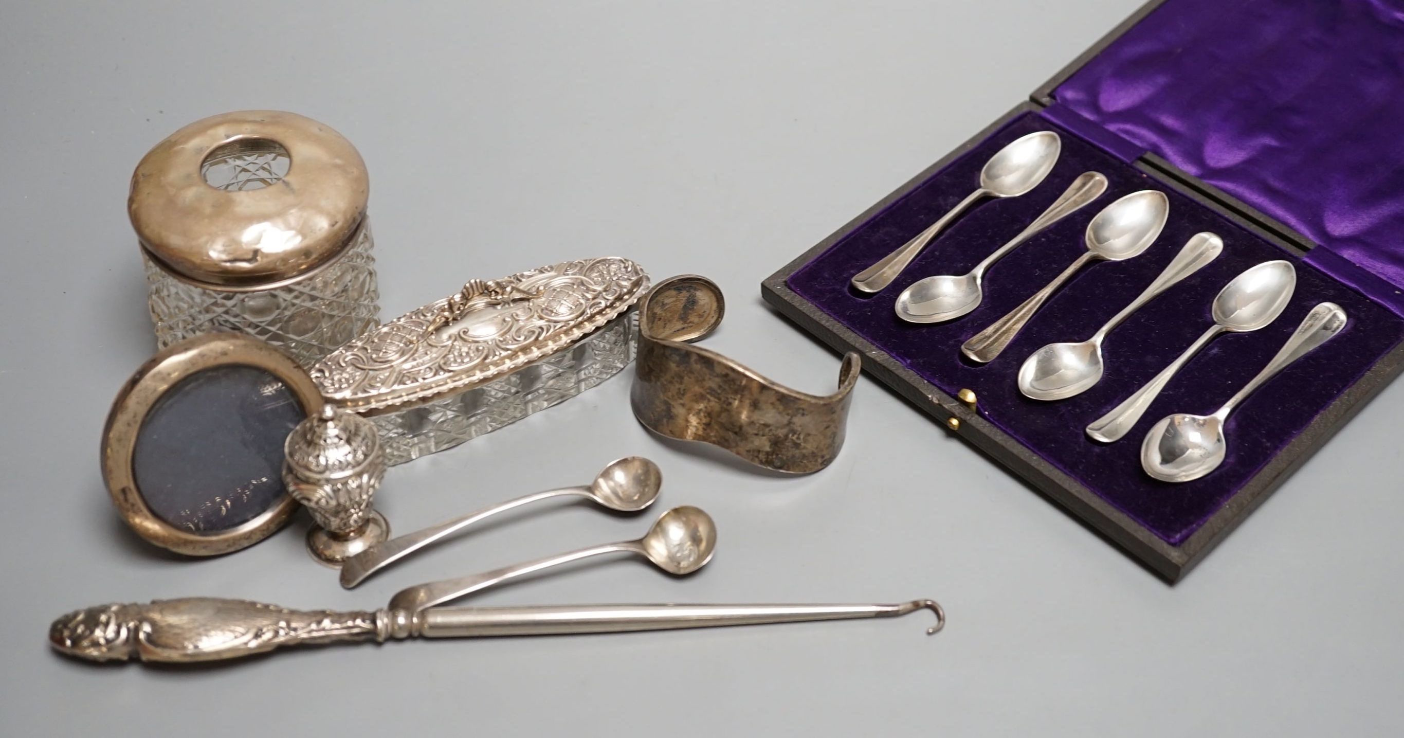 Mixed silver including a cased set of six silver teaspoons, small mounted photograph frame, condiment spoons, toilet jars, button hook, etc.